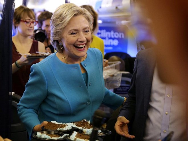 Democratic US presidential nominee Hillary Clinton brings birthday cake to members of the media, as she turn 69, inside her campaign plane en route to New York, US, October 26, 2016. /REUTERS